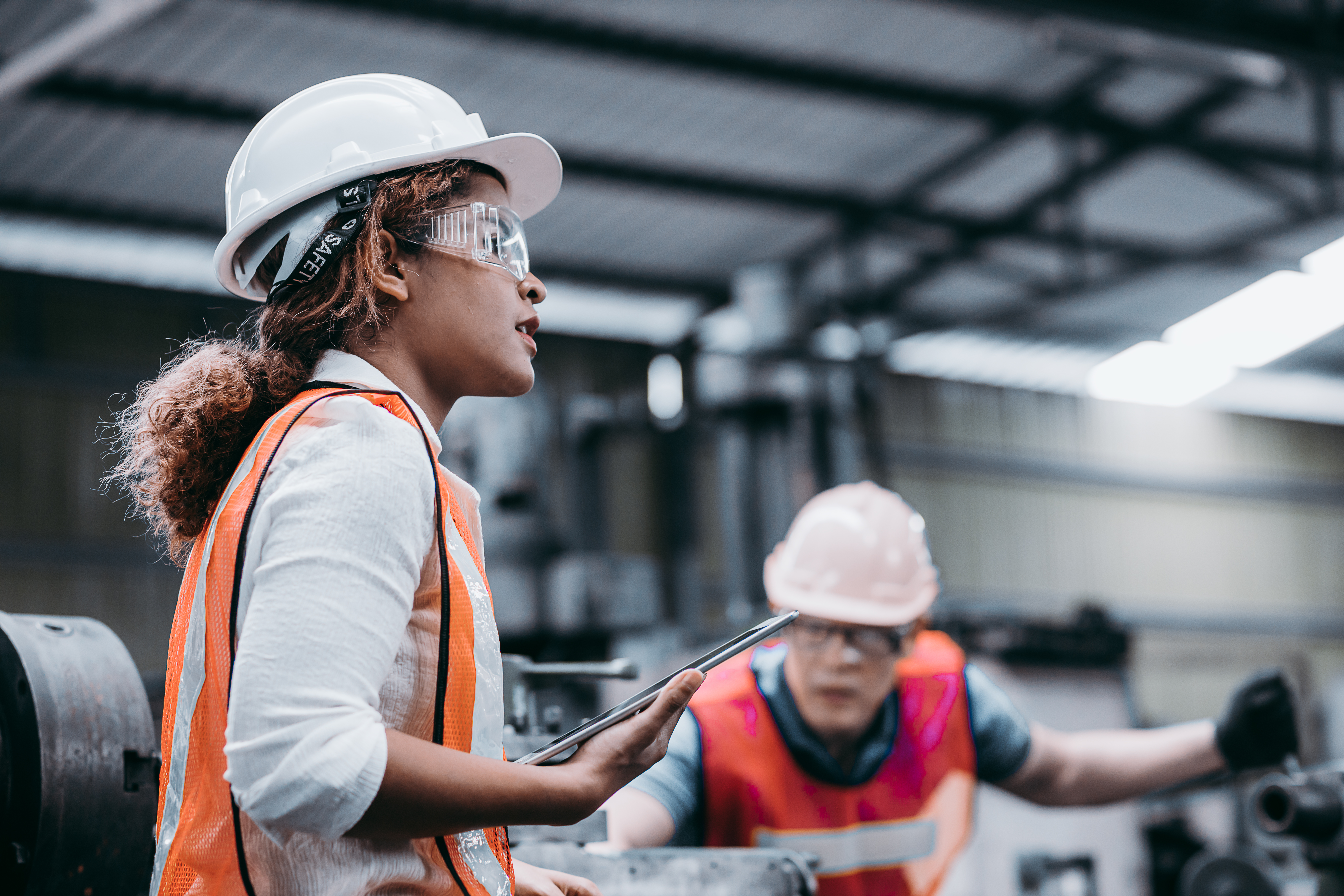Female technician performing inspection on heavy excavator in mining operation